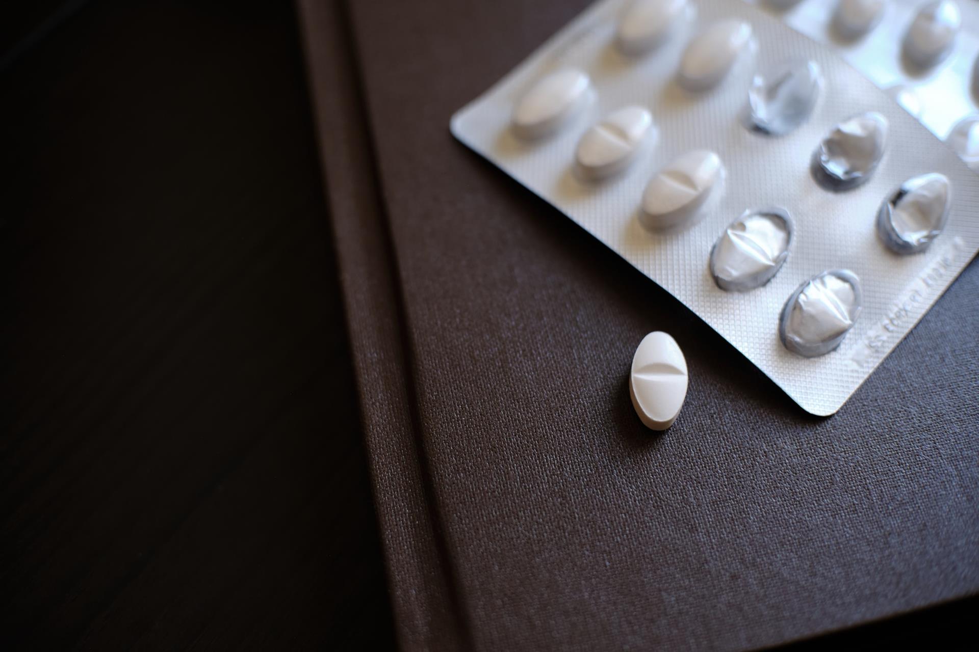A blister pack and a single tablet resting on a desk