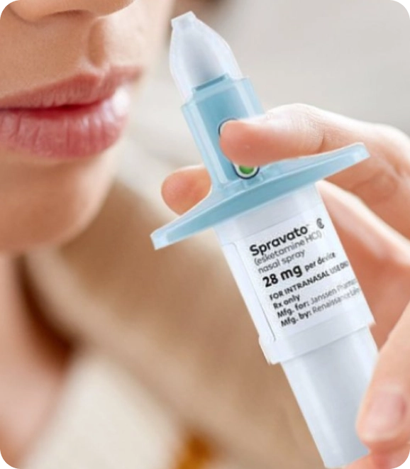 A patient holding the SPRAVATO 28 mg esketamine nasal spray device up to their nose