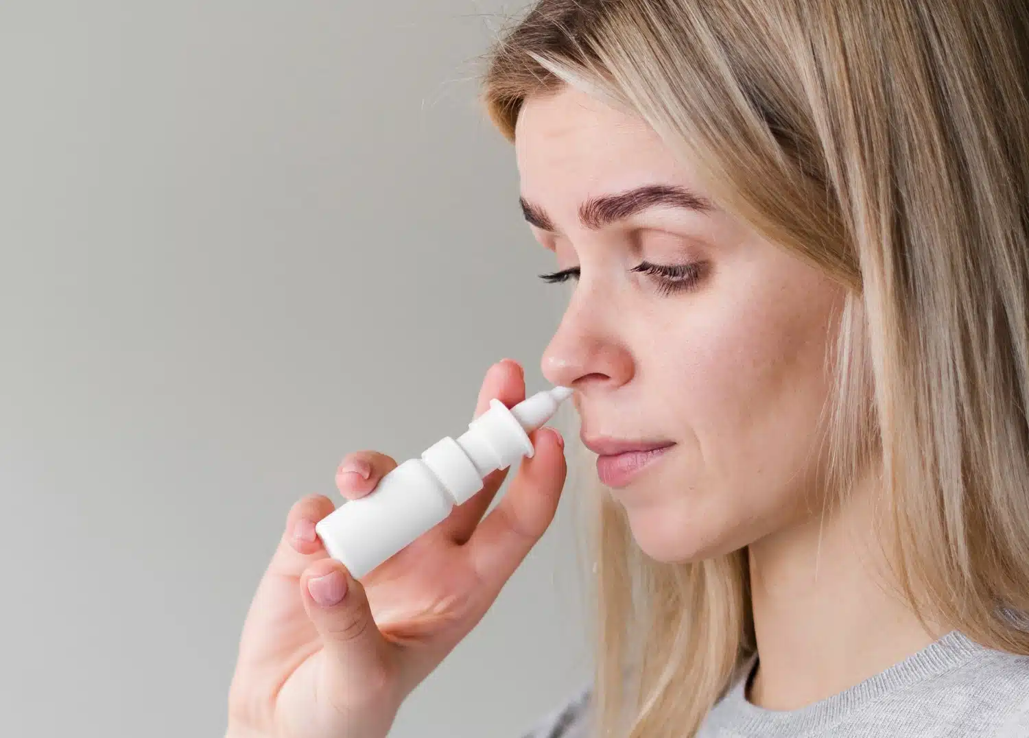 A woman self-administering an esketamine nasal spray