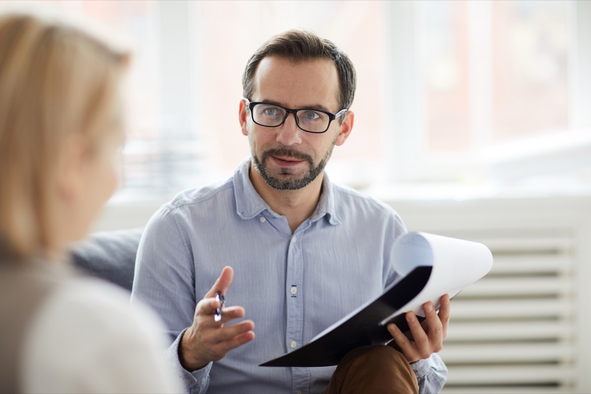 A clinician listening and taking notes while talking with a patient