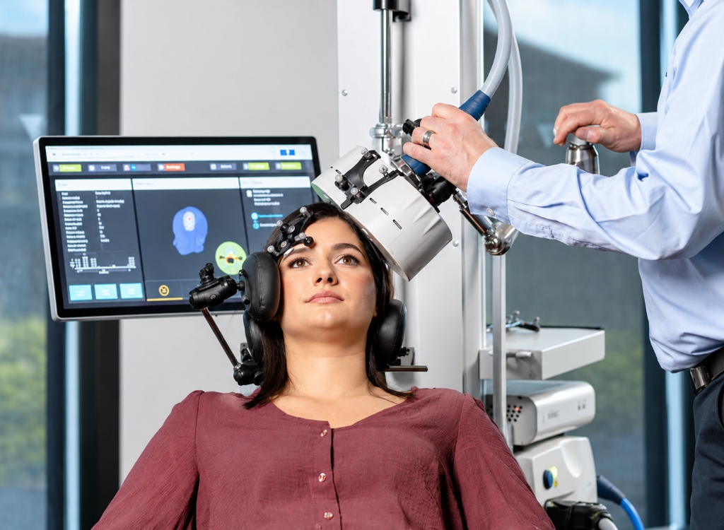 Clinical specialist positioning TMS therapy magnetic coil on patient with neuronavigation system in an interventional psychiatric center